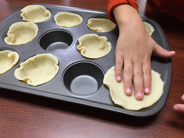 pushing pie crusts into muffin tins